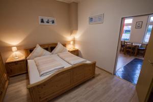 Schlafzimmer mit einem Bett mit weißer Bettwäsche und Kissen in der Unterkunft Haus Pop in Borkum
