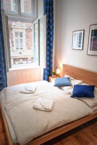 a large bed with two blue pillows and a window at József krt 3BR - near Corvin in Budapest