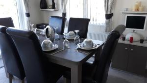 a dining room table with black chairs and a table with dishes at Luxury 6 berth lodge at Quince 10 in Ferndown