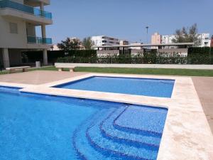 a swimming pool in front of a building at PRECIOSO APARTAMENTO PLAYA DE PILES in Piles