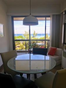 uma sala de estar com uma mesa de vidro e vista para o oceano em Marbella Apart Hotel no Rio de Janeiro