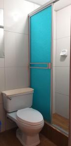 baño con aseo y puerta de ducha azul en Hostal Vista Waynapata 123, en Machu Picchu