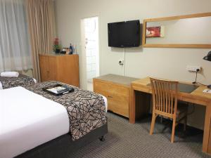 a hotel room with a bed, desk and television at Best Western Endeavour Motel in Maitland
