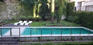 ein Pool mit zwei weißen Stühlen neben einem Gebäude in der Unterkunft Soy Carlos, te espero en Palermo in Buenos Aires