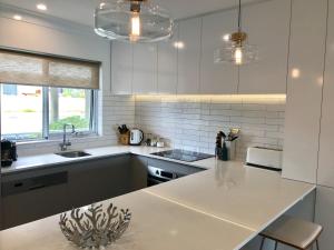 a white kitchen with a sink and a counter at Cottesloe Beachfront Ocean View Apartment in Perth