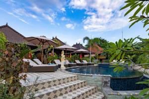 a resort pool with lounge chairs and an umbrella at Karang Mas Lembongan in Nusa Lembongan