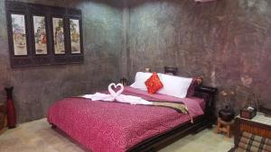 Un dormitorio con una cama rosa con una cinta rosa. en Angels Chambres d'hotes, en Rong Sak