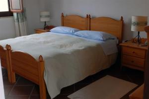 a bedroom with a large wooden bed with blue pillows at Hotel Su Nuraxi in Barùmini