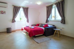 1 dormitorio con 1 cama y 1 sofá con manta roja en Apartment Podini, en Brseč