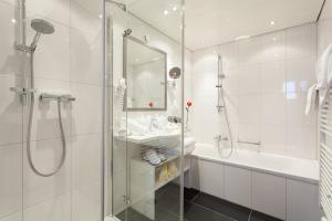 a bathroom with a shower and a sink and a tub at Hotel Enzian in Zürs am Arlberg