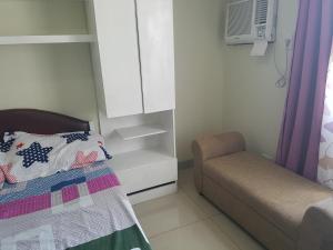 een kleine slaapkamer met een bed en een stoel bij KC Studio 1 at Horizons 101 Cebu in Cebu City