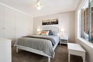 a white bedroom with a bed and a window at 'In The Vines' Guest Cottage, Barossa Valley in Lights Pass