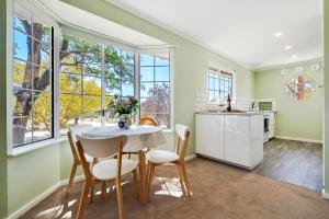 a kitchen with a table and chairs and windows at 'In The Vines' Guest Cottage, Barossa Valley in Lights Pass