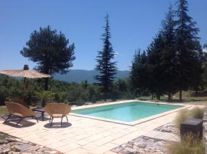 - une piscine avec 2 chaises et un parasol dans l'établissement Le bastidon du Luberon, à Caseneuve