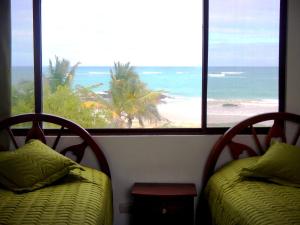two beds in front of a beach with a view of the ocean at Hotel La Jungla in Puerto Villamil