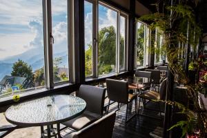 a restaurant with tables and chairs and windows at Zu Sin Garden B&B in Renai