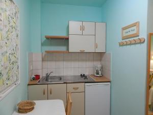 una pequeña cocina con armarios blancos y fregadero en Palmina Mare Villa and Studios, en Paralia Vrachou