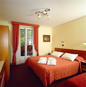 a hotel room with a bed with towels on it at Hotel des Alpes in Molveno