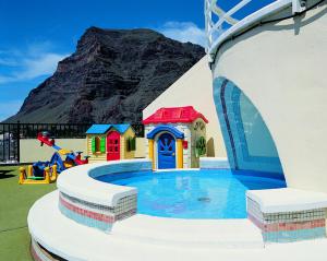 a playground with a pool with a mountain in the background at Hotel Gran Rey in Valle Gran Rey