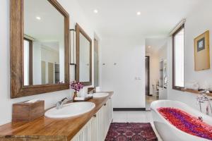 a bathroom with two sinks and a tub and mirrors at Villa Pantai Karang in Sanur +19 photos