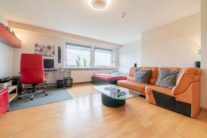 sala de estar con sofá naranja y silla roja en Private Rooms en Hannover