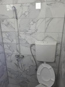 a white bathroom with a toilet and a shower at Edelweiss Hostel in Štip