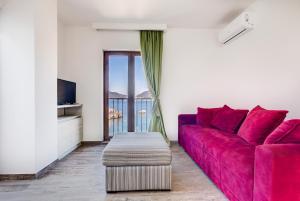 a living room with a red couch and a window at Mima Apartments in Sveti Stefan