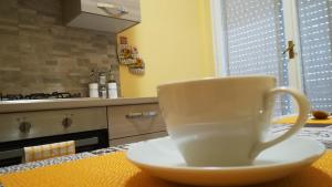 białą filiżankę kawy siedzącą na stole w kuchni w obiekcie Bed Cafe w Syrakuzach