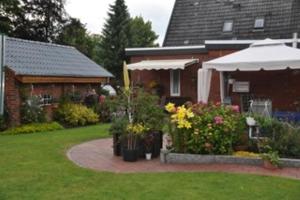 a house with a bunch of flowers in the yard at Fewo Hackländer in Hemmoor