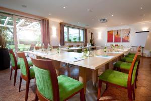 a large dining room with a long table and green chairs at Hotel Sonnenhof in Timelkam