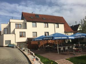 uma casa branca com guarda-sóis azuis, mesas e cadeiras em Gasthof zum Ochsen em Mössingen