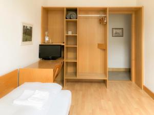 a room with a bed and a desk and a television at Hotel Moon in Düsseldorf