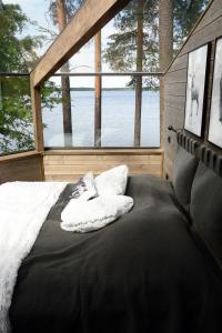 Bett in einer Hütte mit Blick auf das Wasser in der Unterkunft Revontuli Resort Glass Igloos in Hankasalmi