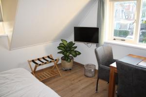 Schlafzimmer mit einem Bett, einem Schreibtisch und einem TV in der Unterkunft Hiltop in Domburg