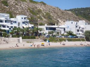 eine Gruppe von Menschen an einem Strand mit Gebäuden in der Unterkunft Chios Xenia Studios & Apartments in Paralia Agias Foteinis