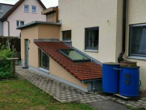 ein Haus mit rotem Dach und zwei Mülltonnen in der Unterkunft Einzelnwohnung mit eigenem Eingang in Weingarten
