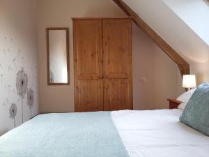 a bedroom with a bed and a wooden cabinet at La petite grange, La vieille ferme in Ruffiac