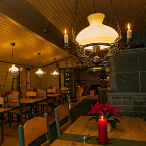 una sala da pranzo con tavoli, sedie e lampadario a braccio di Lappeasuando Lodge a Puoltikasvaara