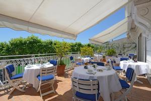 a restaurant with white tables and blue chairs at Hotel Splendid in Cannes
