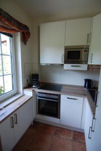una pequeña cocina con armarios blancos y microondas en Landhaus Gohrisch, en Kurort Gohrisch