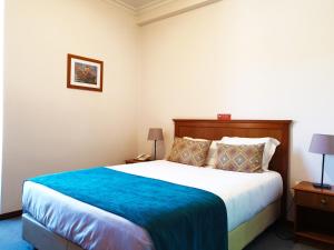 a bedroom with a large bed with a blue blanket at Ninho do Falcao in Sao Pedro de Tomar