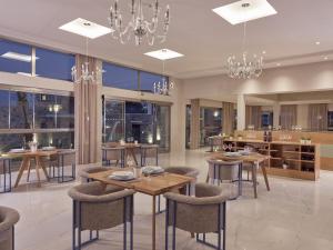 une salle à manger avec des tables, des chaises et des lustres dans l'établissement Golden Sun Resort - Adults Only, à Kalamaki