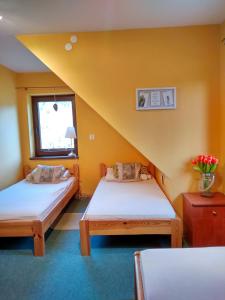 two beds in a room with yellow walls at Tomaszówka in Płaska