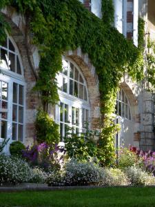 un bâtiment avec des fenêtres et des fleurs devant lui dans l'établissement Logis Hôtel La Tonnellerie, à Beaugency