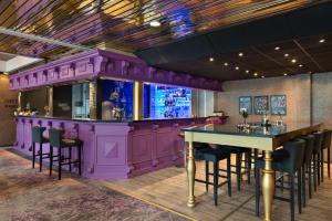 un bar púrpura en un restaurante con mesa y sillas en Clarion Collection Hotel Grand, Gjøvik, en Gjøvik