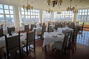 a dining room with white tables and chairs and windows at Parador de Ferrol in Ferrol
