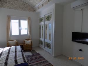 a bedroom with a bed and a tv on a wall at Dar Mamina in Sīdī ash Shammākh