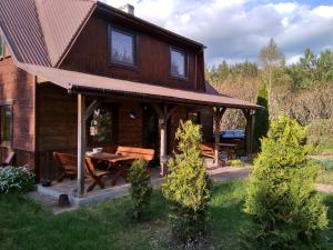 a log cabin with a picnic table in the yard at Tomaszówka in Płaska