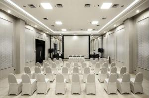 una sala conferenze con sedie bianche e un palco di Hotel Permata Bogor a Bogor Altre 17 foto