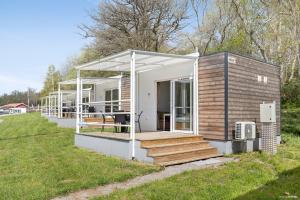 a tiny house with a deck on a field at First Camp Skönstavik Karlskrona in Karlskrona